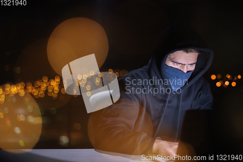 Image of hacker using laptop computer while working in dark office