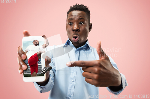 Image of Young man showing screen of mobile phone isolated over coral background