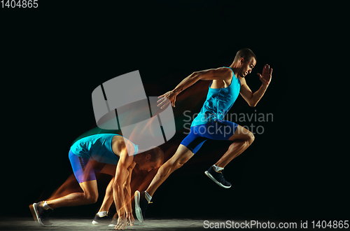 Image of Professional male runner training isolated on black studio background in mixed light