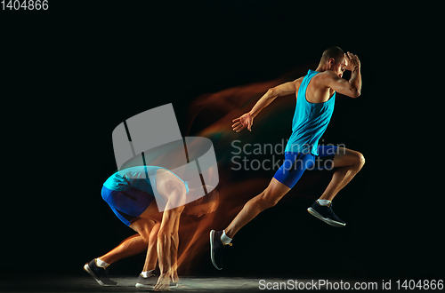 Image of Professional male runner training isolated on black studio background in mixed light