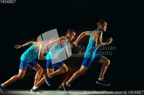 Image of Professional male runner training isolated on black studio background in mixed light