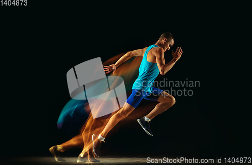 Image of Professional male runner training isolated on black studio background in mixed light