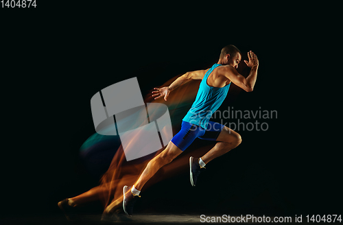 Image of Professional male runner training isolated on black studio background in mixed light