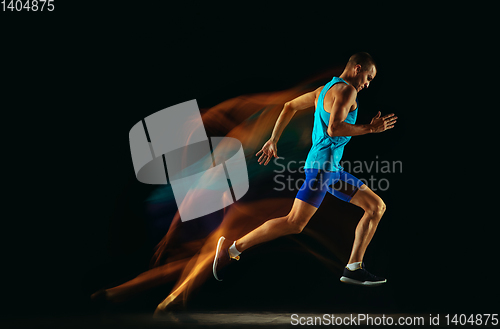 Image of Professional male runner training isolated on black studio background in mixed light