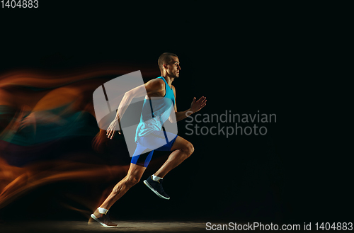 Image of Professional male runner training isolated on black studio background in mixed light