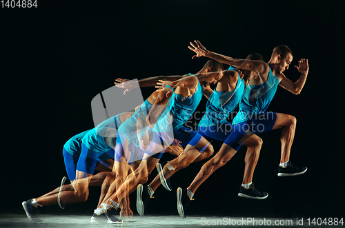 Image of Professional male runner training isolated on black studio background in mixed light