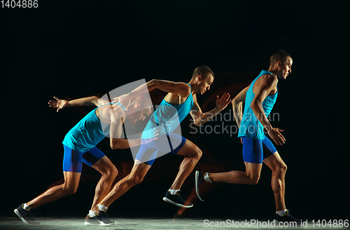 Image of Professional male runner training isolated on black studio background in mixed light