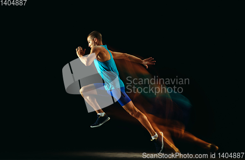 Image of Professional male runner training isolated on black studio background in mixed light