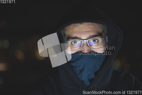 Image of hacker using laptop computer while working in dark office