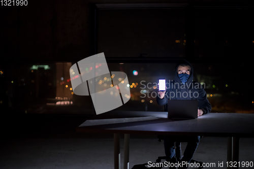 Image of hacker using laptop computer while working in dark office