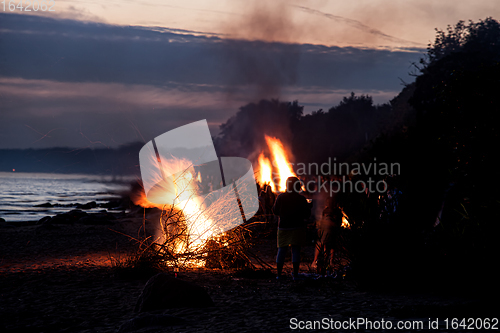 Image of Unrecognisable people celebrating summer solstice with bonfires on beach