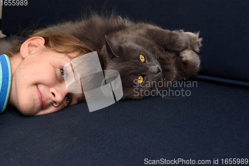 Image of The girl pressed her head to the cat lying on the sofa