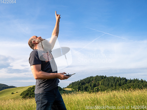 Image of man pointing up to his drone in the sky