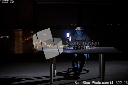 Image of hacker using laptop computer while working in dark office