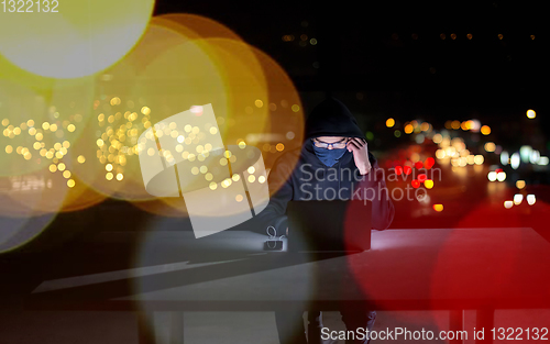 Image of hacker using laptop computer while working in dark office