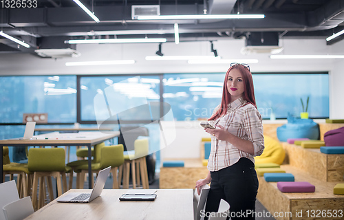 Image of redhead businesswoman using mobile phone at office