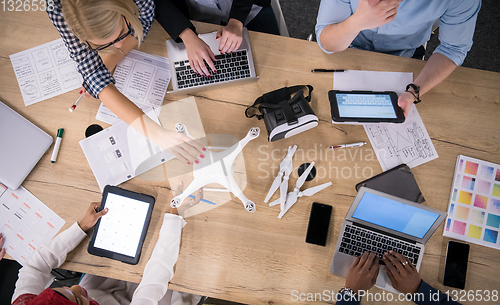 Image of top view of multiethnic business team learning about drone techn