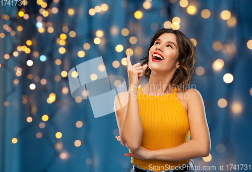 Image of happy smiling young woman pointing finger up