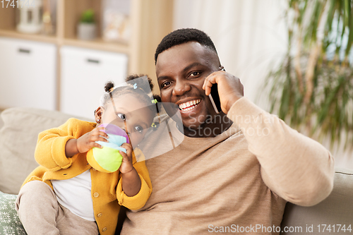 Image of father with baby at home calling on smartphone