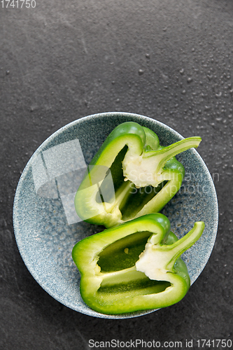 Image of cut green pepper in bowl on slate stone background