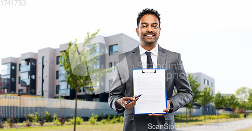 Image of indian man realtor with contract on city street