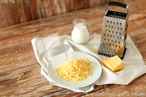 Image of close up of grated cheese and jug of milk on table