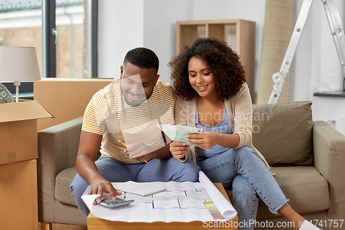 Image of couple with blueprint counting money at home