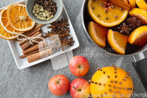 Image of pot of hot mulled wine, orange, apples and spices