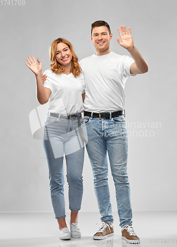 Image of happy couple in white t-shirts waving hands