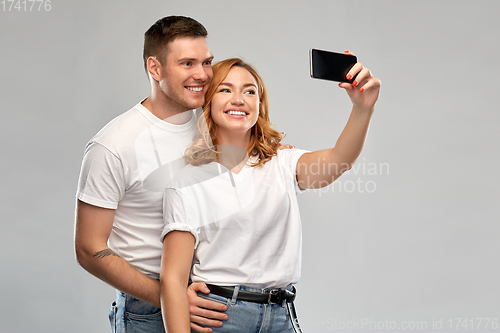 Image of happy couple in white t-shirts taking selfie