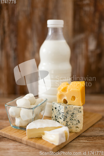 Image of different kinds of cheese and milk on wooden board