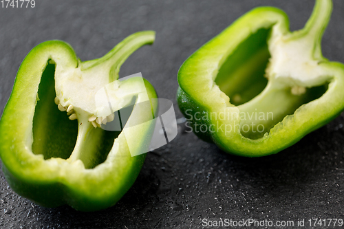 Image of cut green pepper on slate stone background