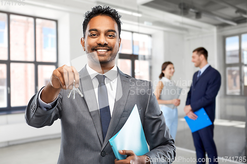 Image of indian man realtor with keys at empty office room