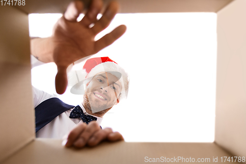 Image of happy young man looking into open christmas gift