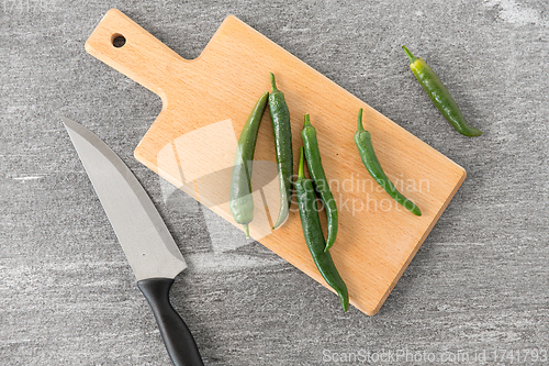 Image of green chili peppers and knife on cutting board