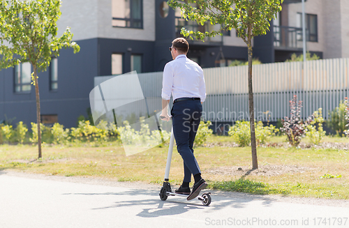 Image of young businessman riding electric scooter outdoors