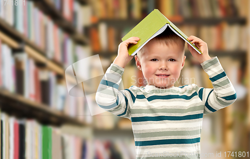 Image of smiling boy with book on head over library