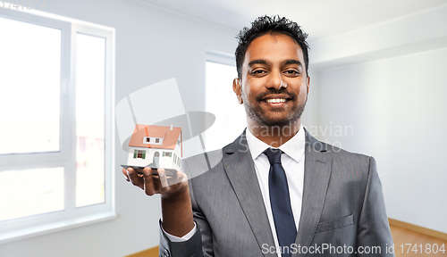 Image of indian man realtor with house model at new home