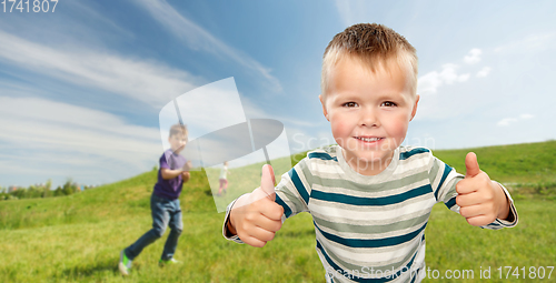 Image of smiling boy showing thumbs up outdoors