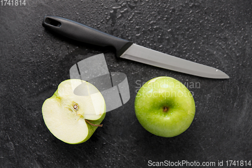 Image of green apples and kitchen knife on slate background