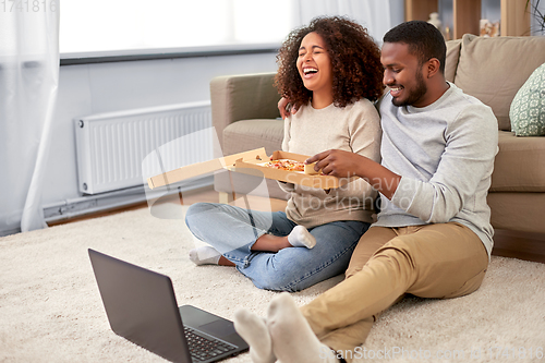 Image of happy african american couple eating pizza at home