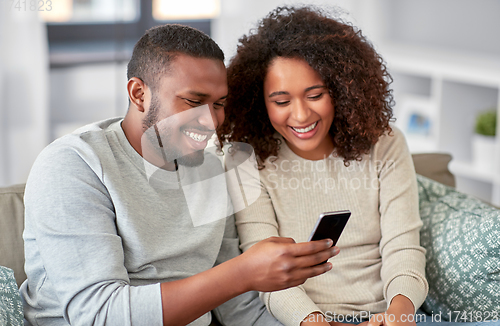 Image of african american couple with smartphone at home