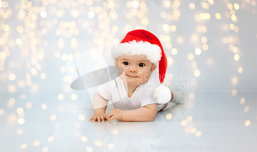 Image of little baby in santa helper hat lying on floor