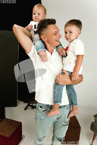 Image of Happy father holding adorable little sons and smiling