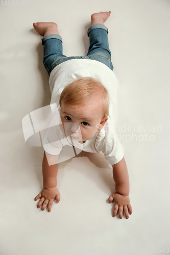 Image of Little boy lying down on floor and looking up to the side