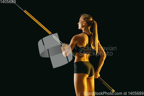 Image of Female pole vaulter training on black studio background in neon light