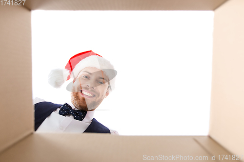 Image of happy young man looking into open christmas gift