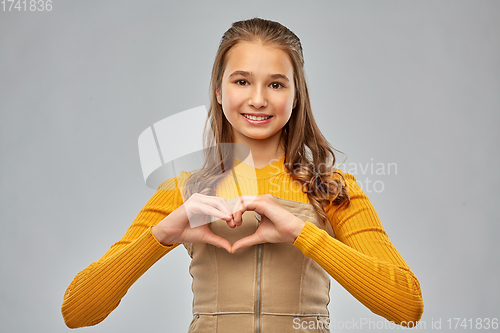 Image of smiling teenage girl making hand heart