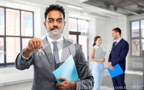 Image of indian man realtor with keys at empty office room