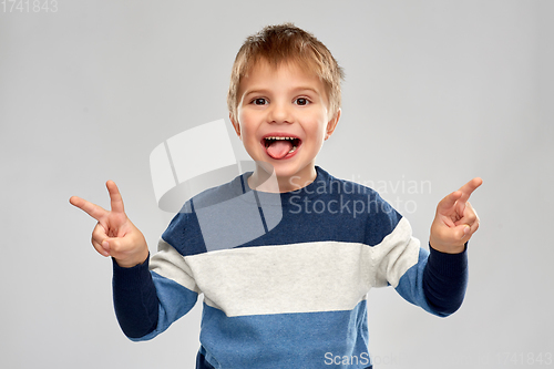 Image of little boy in striped pullover showing peace